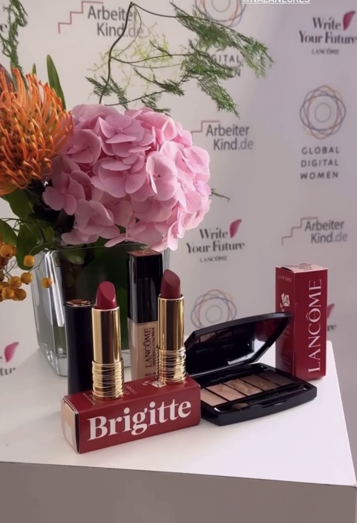 Floral arrangement with protea and hydrangea beside Lancôme products at a brand event